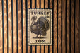 A metal stamp featuring a turkey on a wooden background.