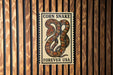 a sign with a large, colorful snake on it, mounted on a wooden wall.