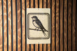 A sign featuring a black and white illustration of a bird perched on a branch.