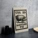 A sign featuring a pig illustration and text, placed on a table next to some black camera lenses.