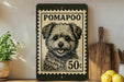 A black and white illustration of a pom-poo dog on a postage stamp, with the text "POMAPOO" and "50c" printed on it. The stamp is placed on a shelf next to a wooden cutting board and a potted plant.