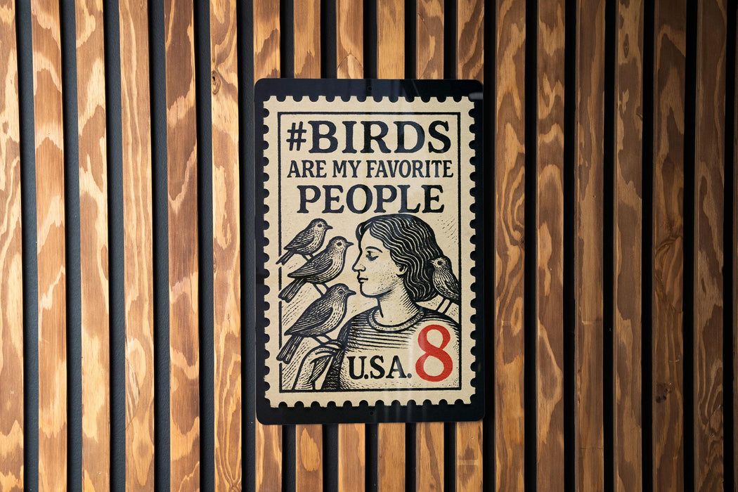 A stamp-like sign with the text "#BIRDS ARE MY FAVORITE PEOPLE" and a portrait of a woman with birds on her shoulder, mounted on a wooden wall.