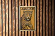 A metal sign with a jaguar illustration is mounted on a wooden wall.