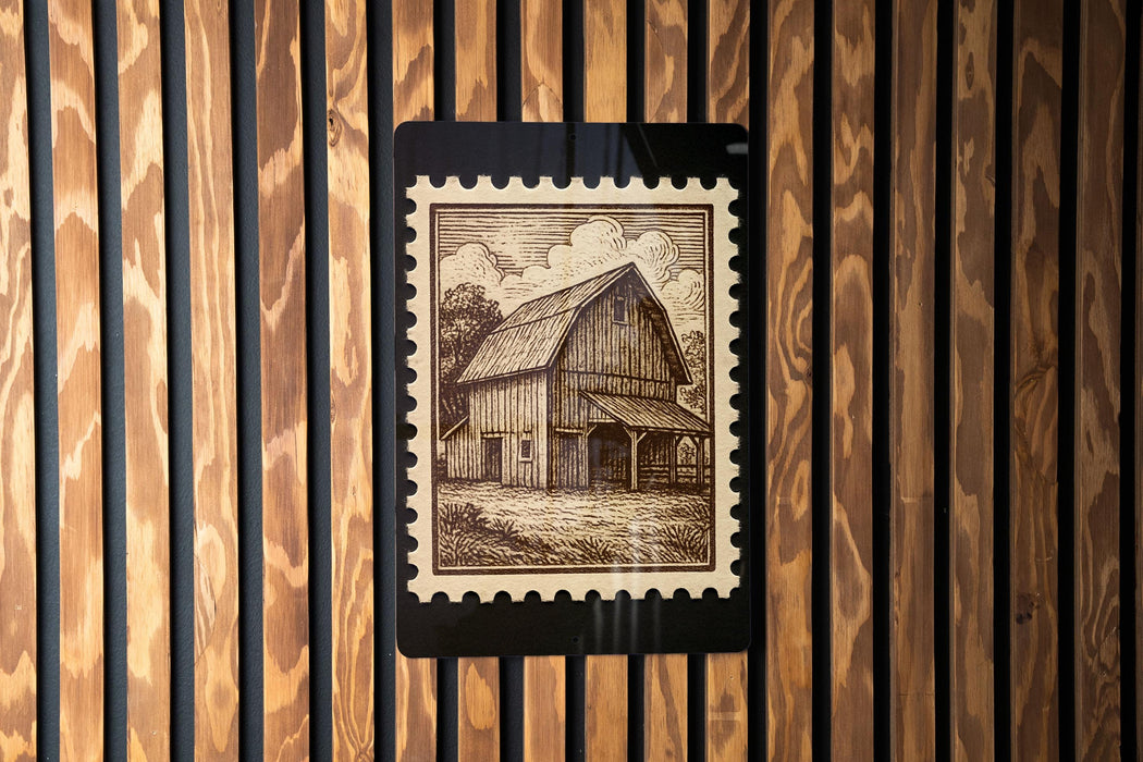 A wooden wall with a framed image of a barn, which appears to be a postage stamp.