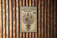 A vintage-style metal sign with a floral design, mounted on a wooden wall.