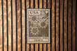 A wooden fence with a USA 25 25 Passionflower Fence sign hanging on it.