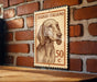 A wooden table with a brick wall in the background, featuring a framed Italian postage stamp depicting a dog.
