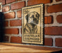 A metal sign featuring a black and white illustration of a Anatolian Shepherd dog, mounted on a brick wall.