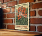 A metal sign with a floral illustration is mounted on a brick wall.