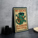 A metal sign with a cartoon gecko wearing sunglasses and the text "MY GECKO IS COOLER THAN YOUR 15¢" is displayed on a table.