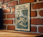 a vintage-style metal sign with a drawing of a letter writing desk, mounted on a brick wall.