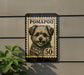 A black and white postage stamp featuring a dog's face is displayed on a wall, with a plant visible to the left.