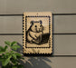 a small, cartoonish hamster sitting on a laptop computer, which is depicted in a stamp-like frame.