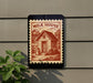 a small wooden house with a red and white stamp-like design on the wall, depicting a rural scene with a cow and a barn.