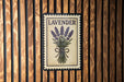 A framed image of lavender flowers is displayed on a wooden wall.