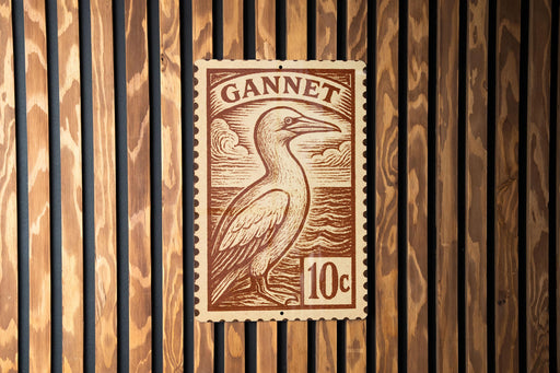 A brown postage stamp featuring a bird, likely a gannet, is displayed on a wooden wall.