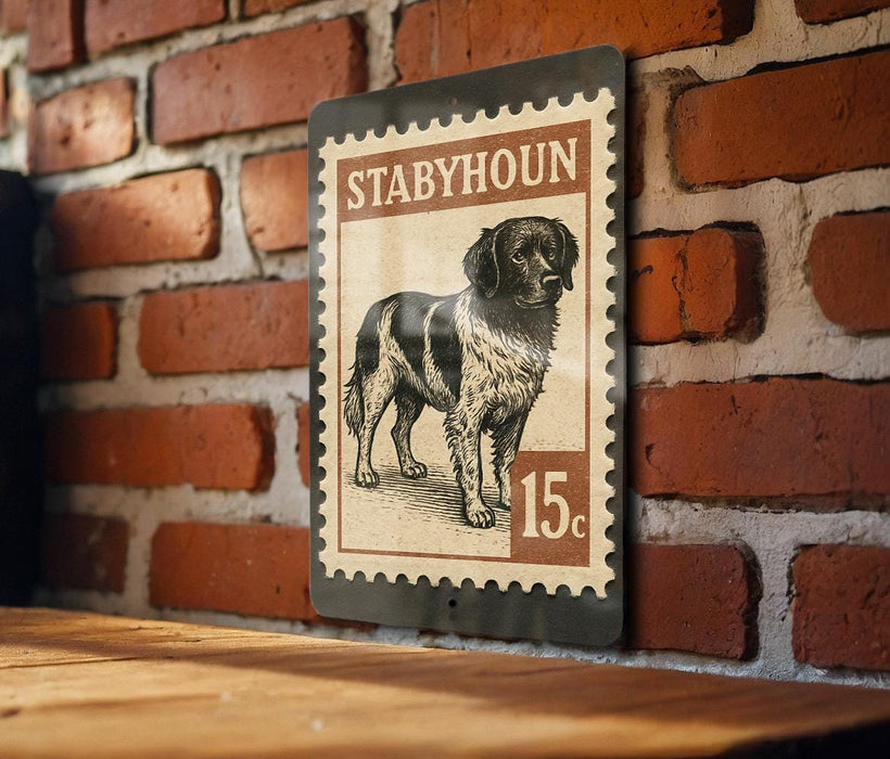 A metal sign with a stamp-like design, featuring a black and white illustration of a dog, mounted on a brick wall.