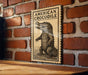 a wooden table with a framed illustration of an American crocodile on it, mounted on a brick wall.