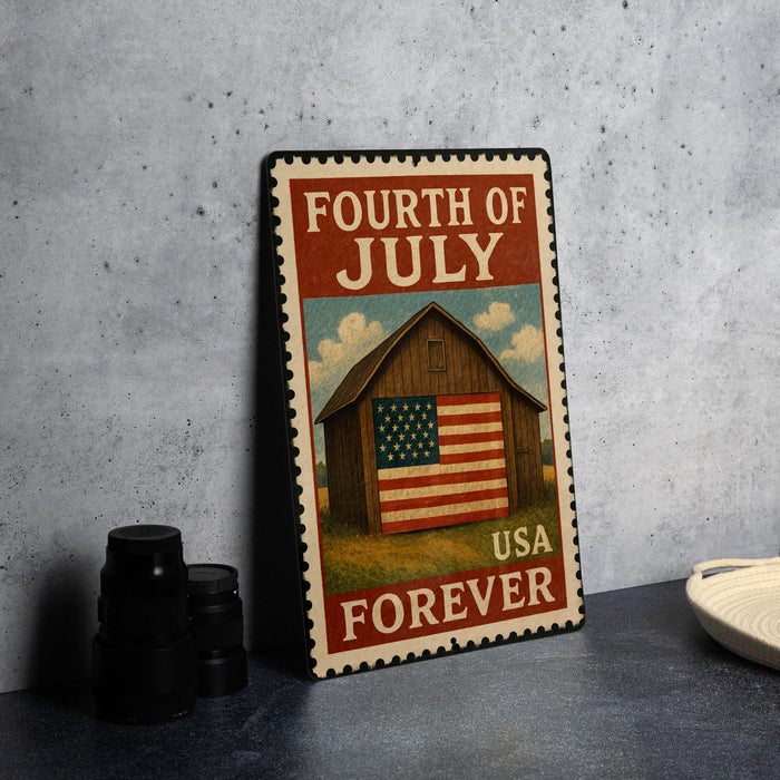 A metal sign with a wooden barn and American flag, displaying the text "FOURTH OF JULY USA FOREVER" on a gray wall.
