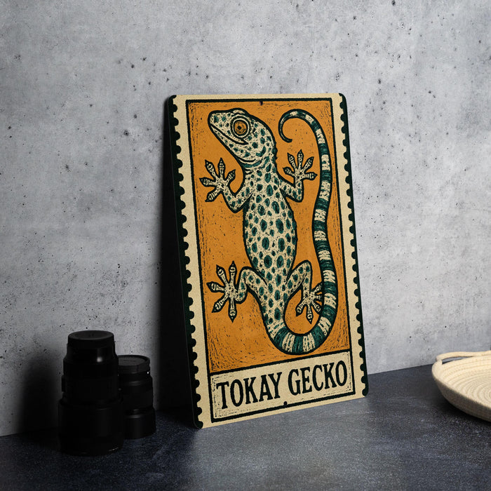 a metal sign with a gecko illustration, placed on a table next to some black camera lenses.