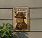 a sign with a picture of a rabbit wearing a hat and coat, mounted on a wall.