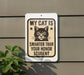 a sign with a cat on it, mounted on a wall.