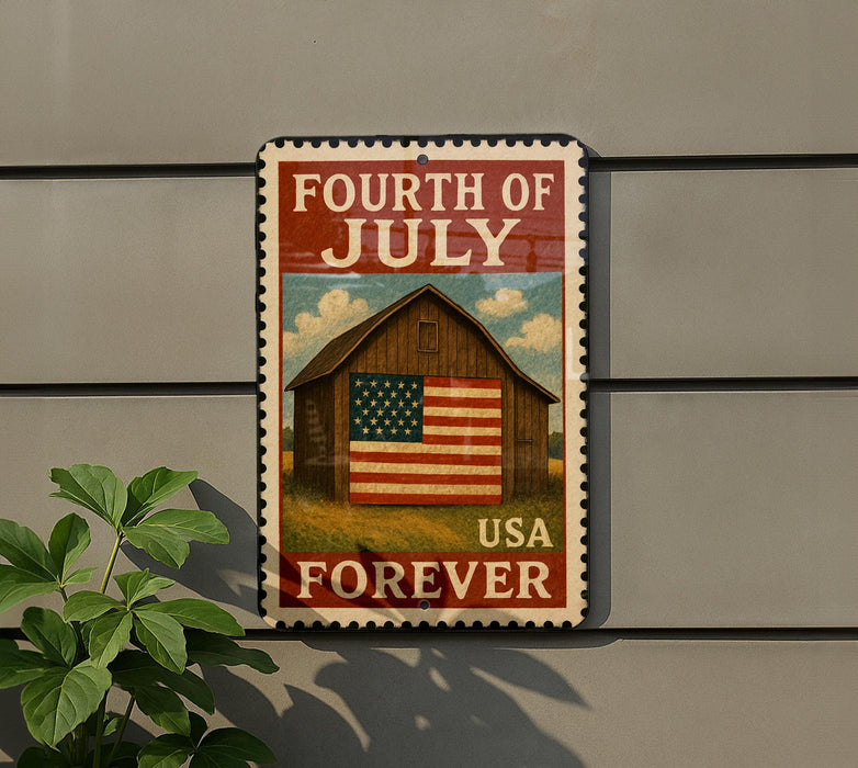 A patriotic sign celebrating the Fourth of July, featuring a wooden barn and an American flag, mounted on a gray wall.