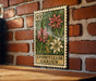 A vintage-style postage stamp featuring a floral design, hanging on a brick wall.