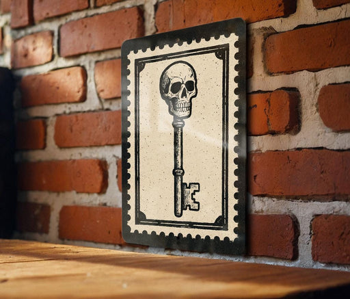 A framed image of a skull with a key is displayed on a brick wall.