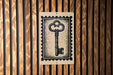 A black and white key-shaped stamp is displayed on a wooden wall.