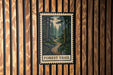 A framed image of a forest trail is displayed on a wooden wall.