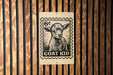 A wooden wall with a black and white stamp-like sign featuring a goat's face and the text "GOAT KID" printed on it.