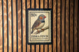 A postage stamp featuring a zebra finch, with the text "Zebra finch Taeniopia guttata" printed on it.