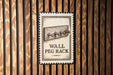 A wall peg rack sign is displayed against a wooden background.