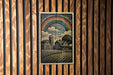 A framed illustration of a rural landscape with a rainbow in the sky, depicting a farm scene with buildings and a silo.