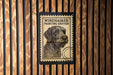 A postage stamp featuring a dog's head is displayed on a wooden wall.
