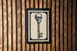 a key with a skull on it, which is mounted on a wooden wall.