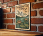 A sign depicting a dragonfly pond hangs on a brick wall, featuring a dragonfly and lily pads.