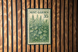 A metal sign with a mint plant illustration is mounted on a wooden wall.