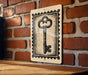 a brick wall with a wooden table in front of it. There is a key-shaped stamp or sign hanging on the wall, which appears to be a decorative piece.