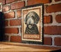 A metal sign featuring a black and white illustration of a curly-haired dog, with the text "AUSSIEDDoodle" printed on it, mounted on a brick wall.