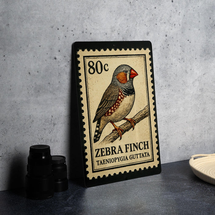 A metal stamp depicting a zebra finch, with the text "80c ZEBRA FINCH TAENIOPIGIA GUTTA" printed on it.