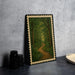 a framed painting of a forest path with a winding trail, placed on a dark surface next to a stack of black camera lenses.
