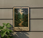 A metal sign with a forest trail painted on it, mounted on a wall next to a plant.