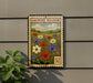 a vintage-style metal sign with a floral design, mounted on a wall next to a plant.