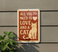 a sign with a cat illustration and text that reads "All you need is love and a cat".