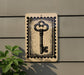a key-shaped sign on a wall, with a plant to the left of the sign.