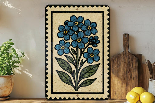 a decorative tile with a blue flower design, placed on a wooden surface next to a wooden cutting board and a potted plant.