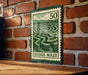 A green and white stamp-like design depicting a hedge maze, mounted on a brick wall.