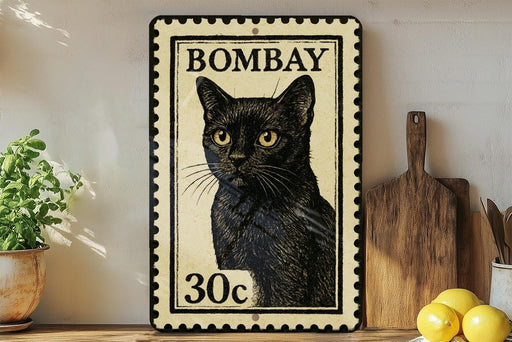 A vintage-style stamp depicting a black cat, with the text "BOMBAY 30c" printed on it. The stamp is placed on a shelf next to a wooden cutting board and a potted plant.